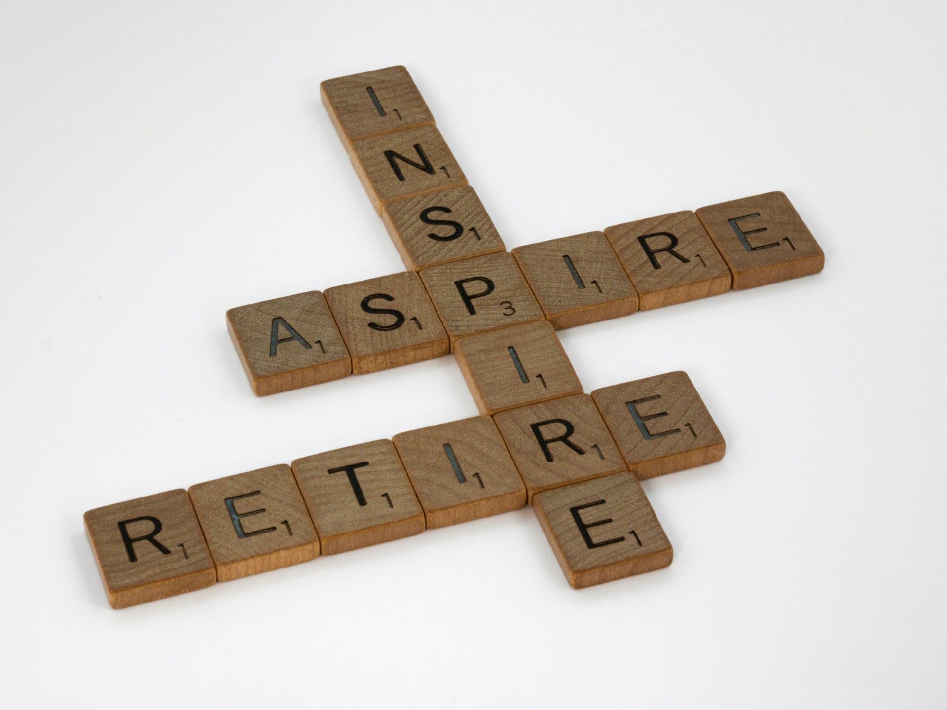 interconnected scrabble tiles showing RETIRE, ASPIRE, INSPIRE