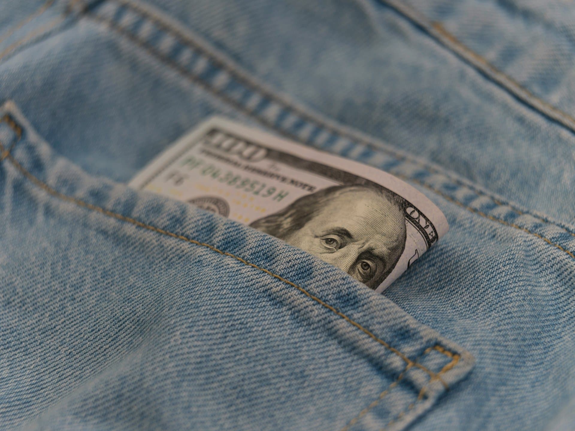 a dollar bill peeping out of a jeans back pocket