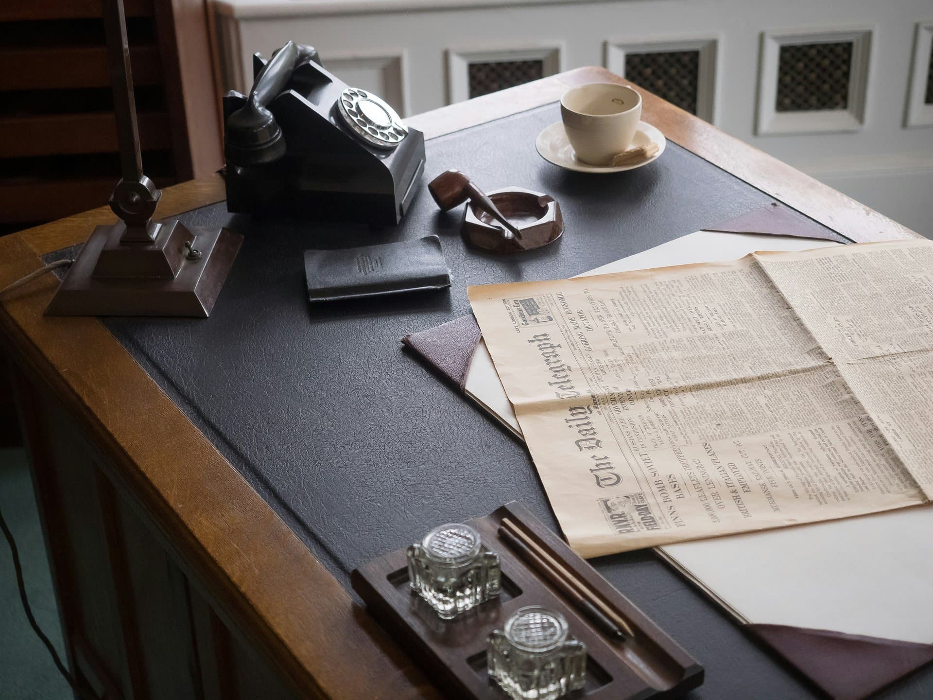 an office desk with a newspaper and telephone