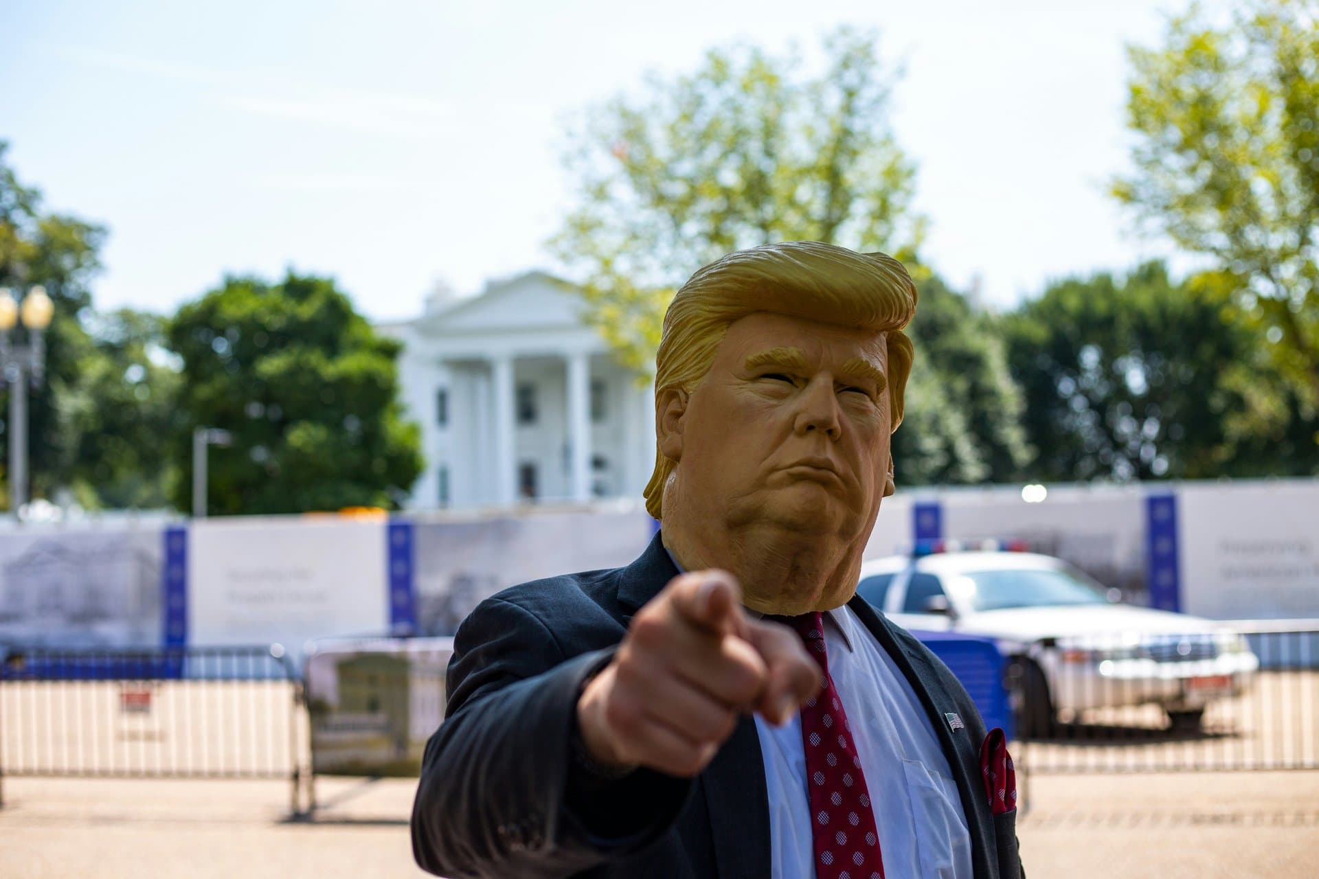 a person wearing face mask of donald trump pointing a finger