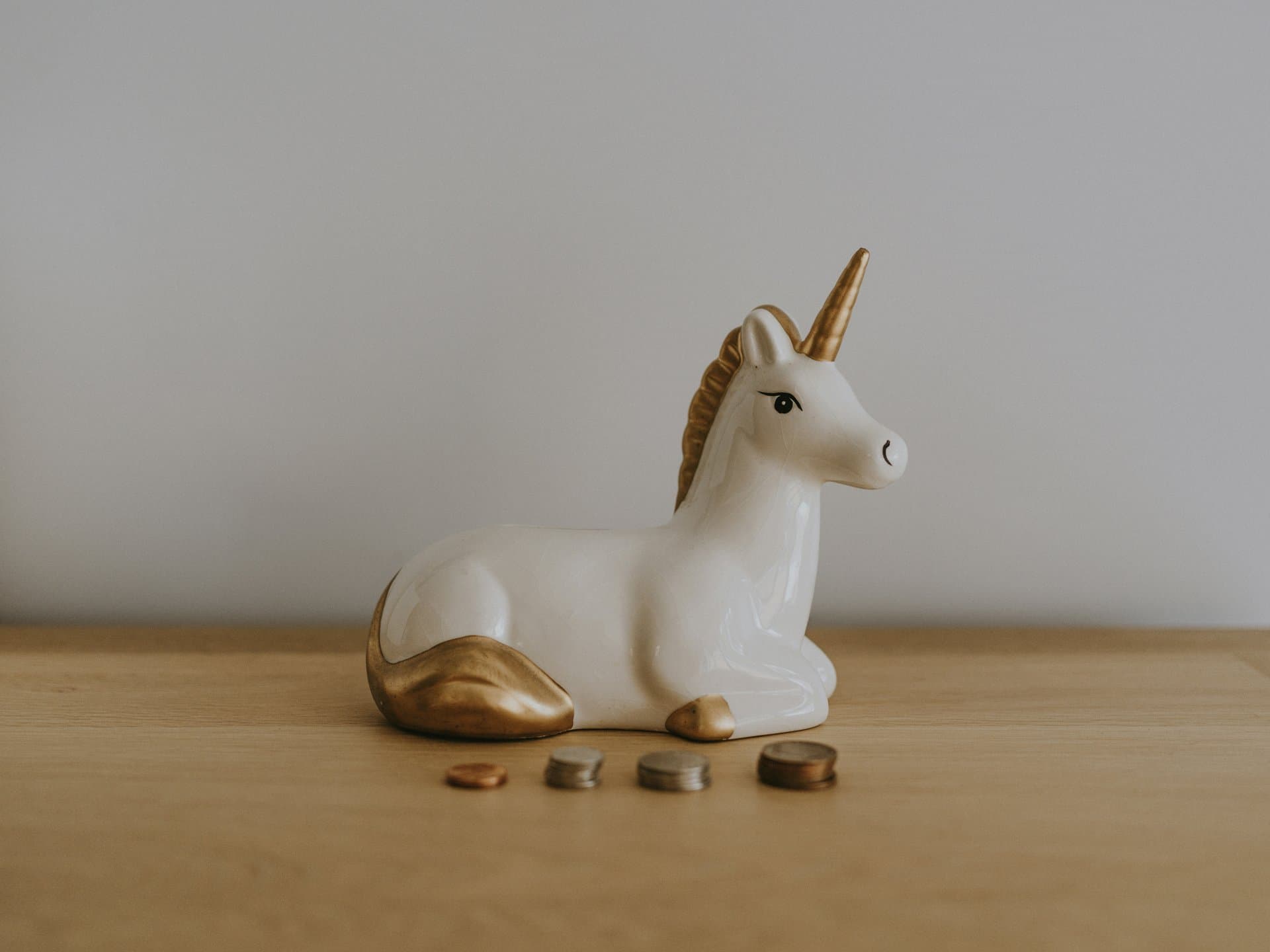 a unicorn toy sitting next to pile of coins