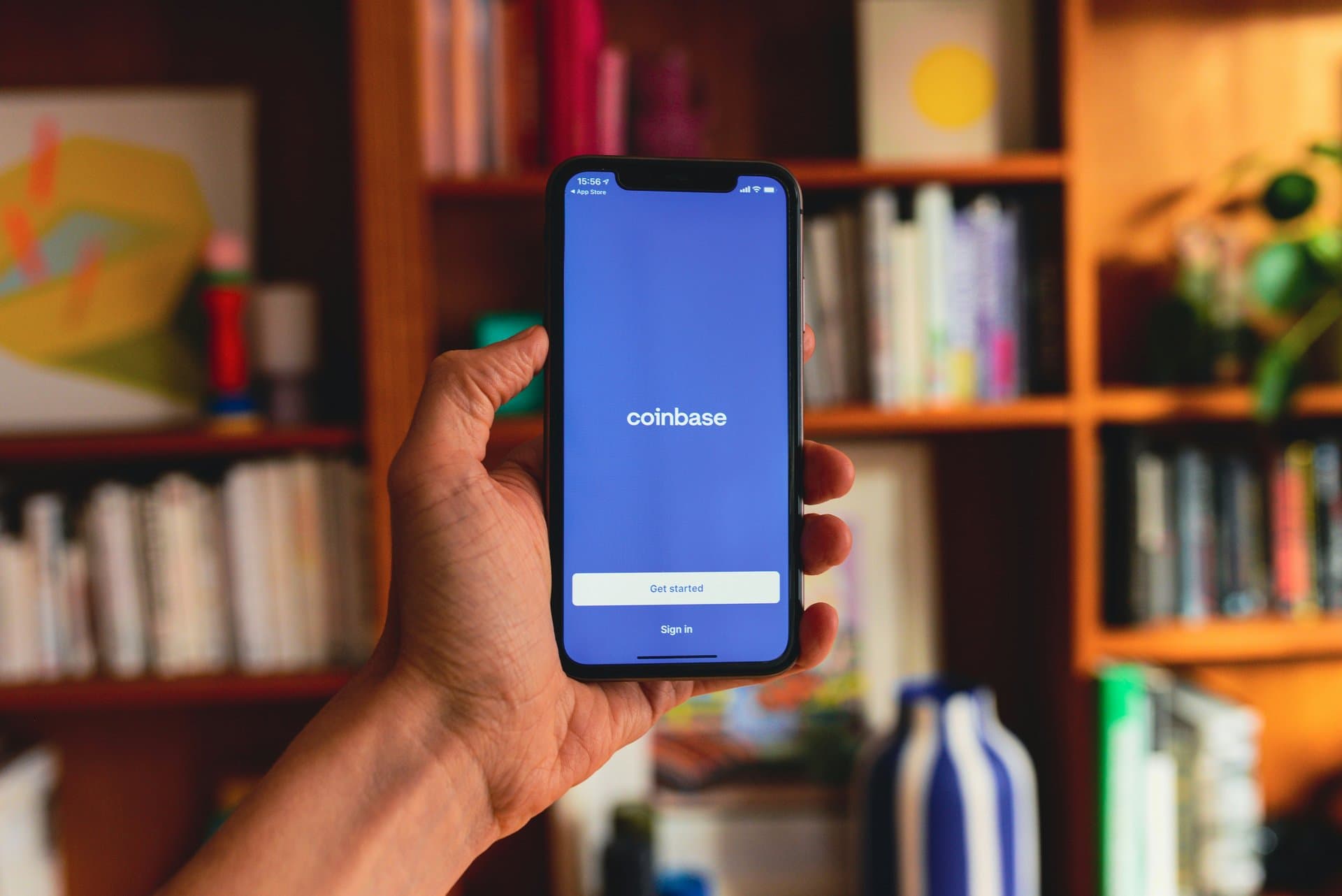 a hand holding a smartphone with Coinbase App opened