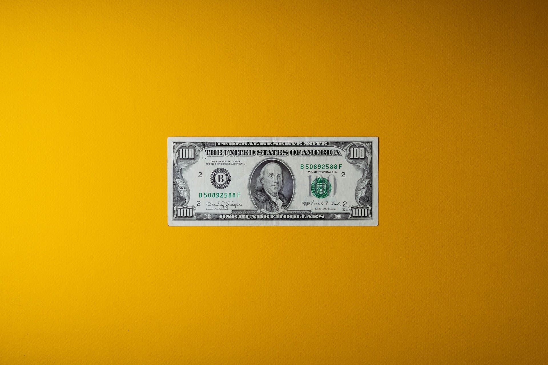 a dollar bill on a bright yellow wall
