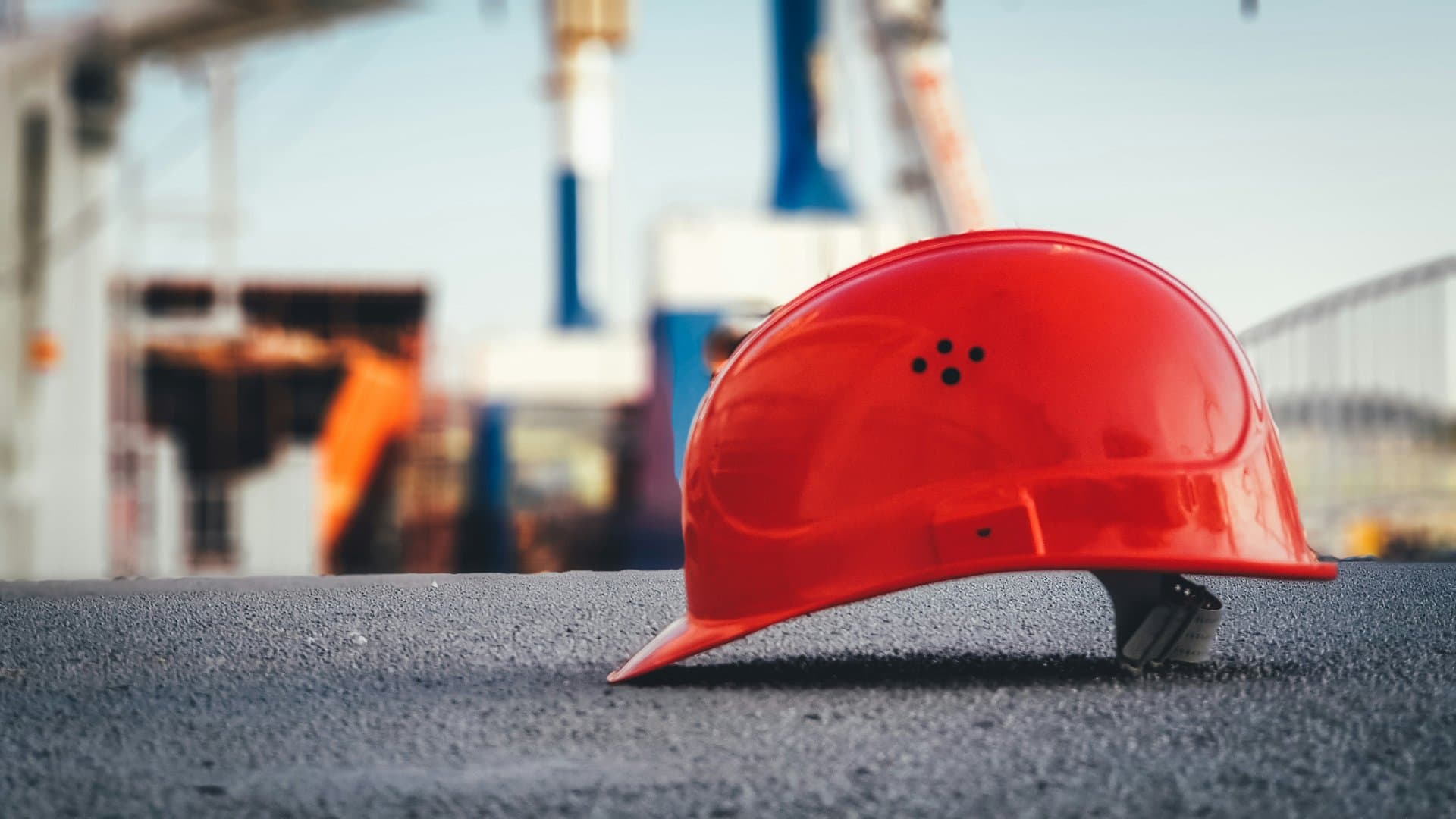 a red helmet with an oilfield in the background