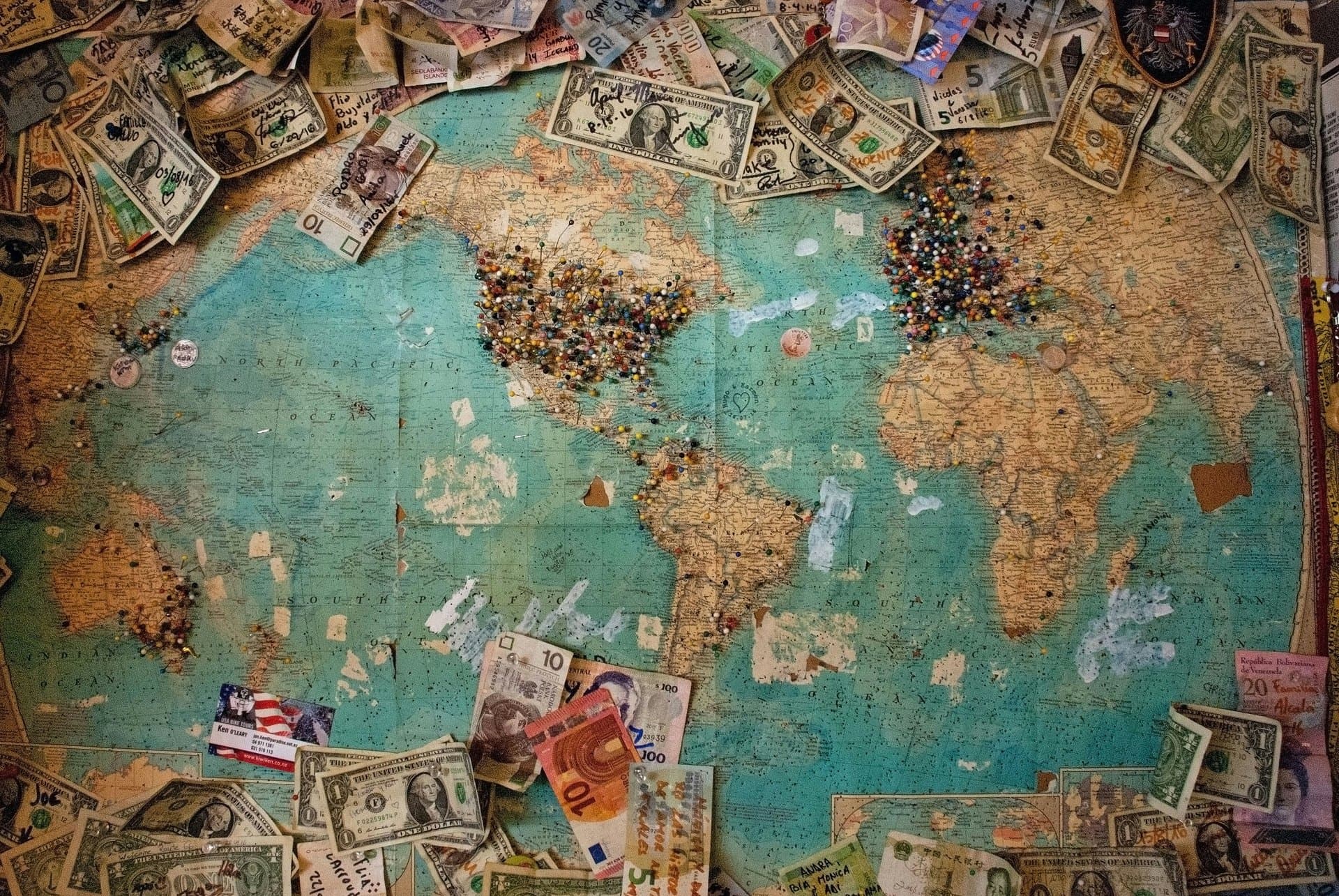 multiple currency bills placed on a large world map