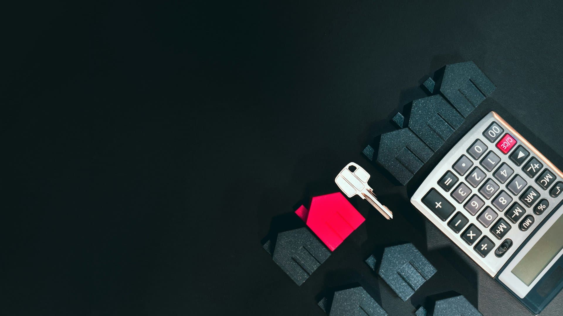 a key, a calculator and some house-like toys on a black table