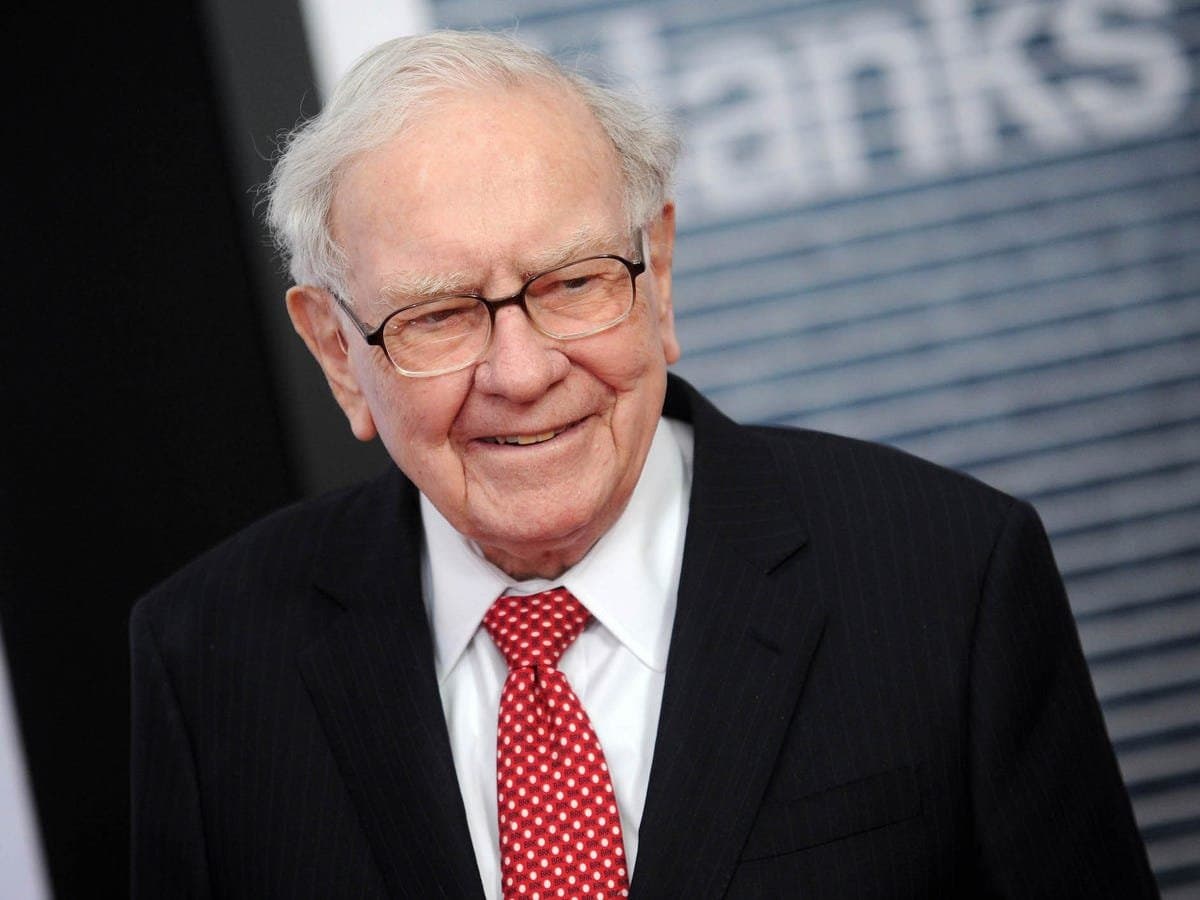 Warren Buffett wearing a black suit and a red tie