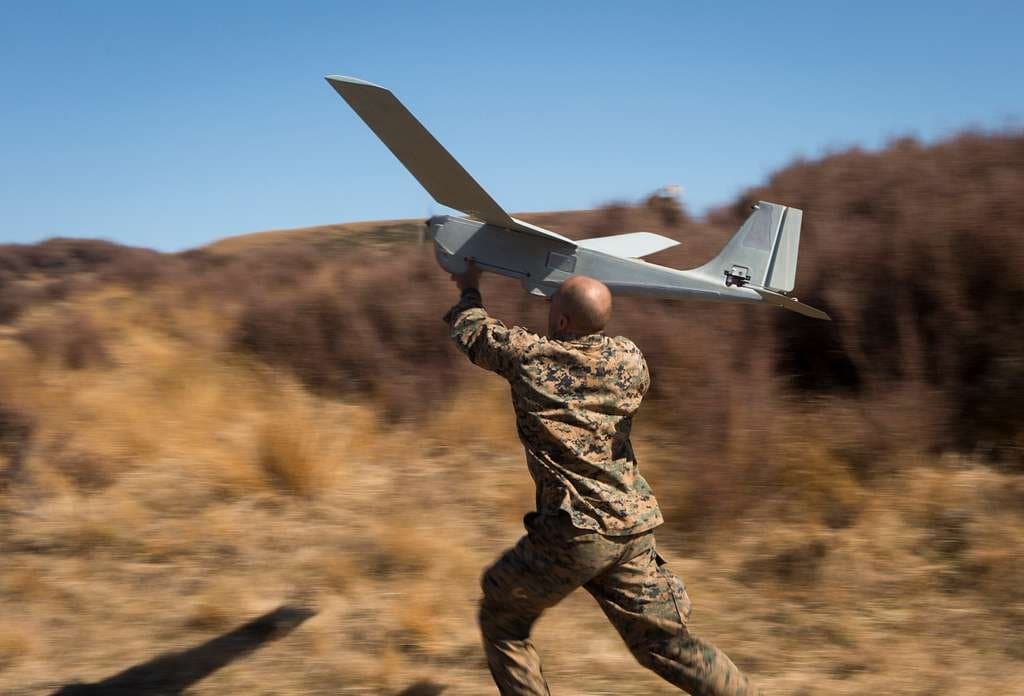 a soldier holding a drone plane in hands