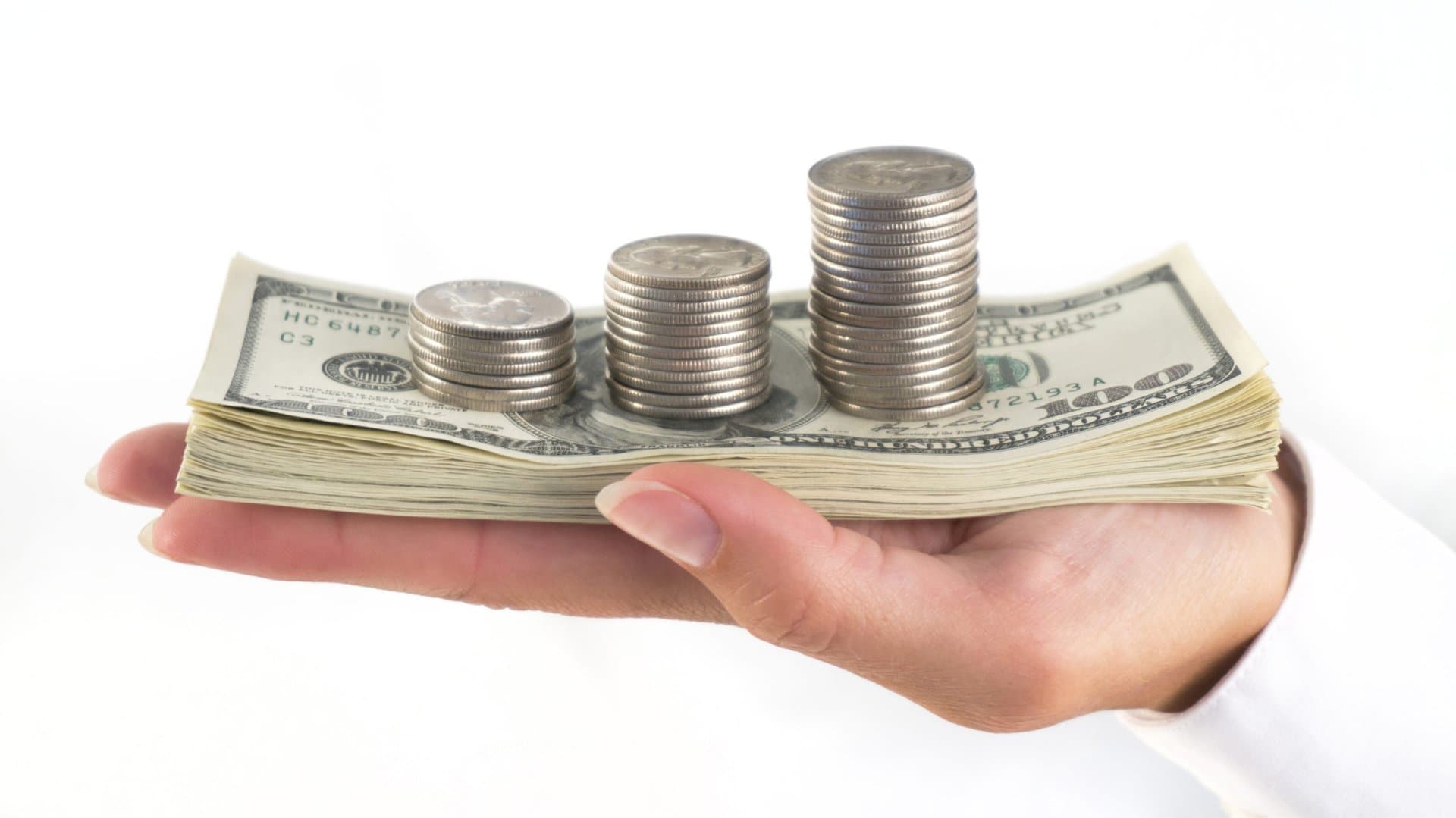a bundle of dollars with some pile of coins on it