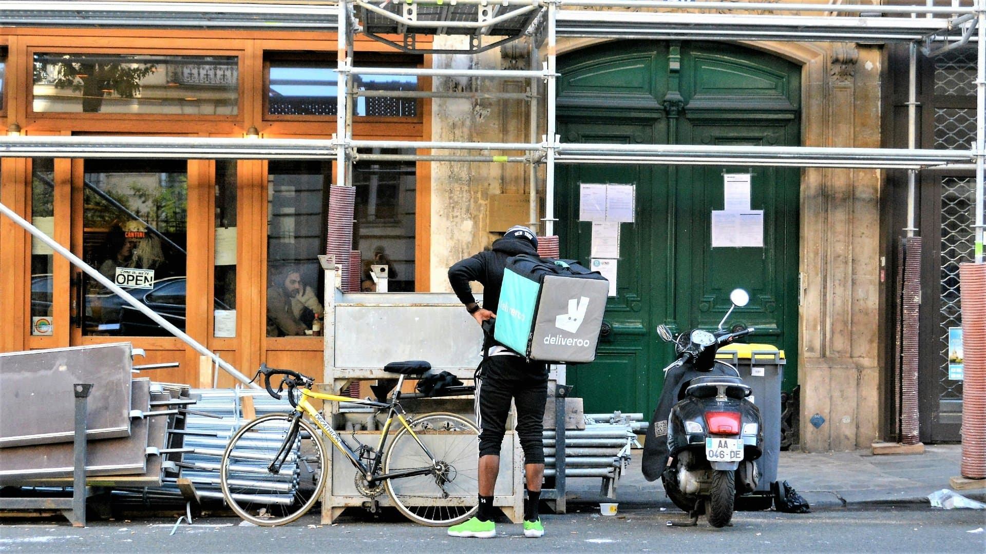 A Deliveroo rider standing near restaurants